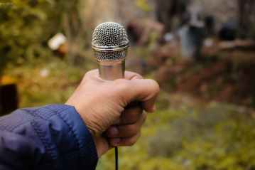 person holding grey corded microphone in selective focus photography photo taken